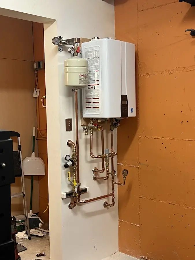 Plumbing technician inspecting water heater connections in Neosho